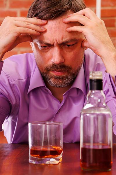 мужчина сидит за столом перед стаканом с алкоголем